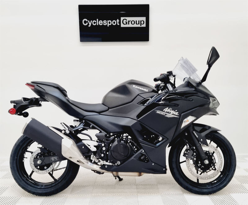 Load image into Gallery viewer, Black Kawasaki Ninja 500 motorcycle on a white floor with 'Cyclespot Group' sign in the background