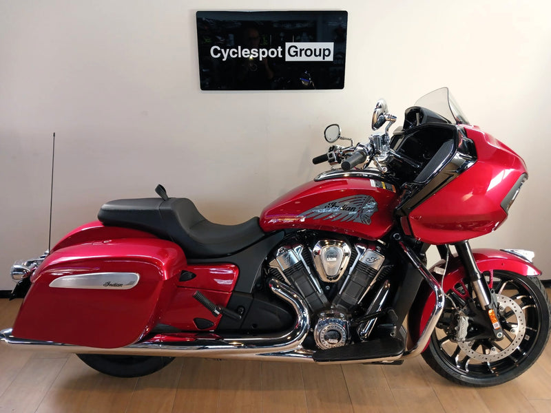 Load image into Gallery viewer, A red and black Indian Challenger Ltd motorcycle is parked indoors against a beige wall with a 'Cyclespot Group' sign above it. The bike features a large windscreen, saddlebags, chrome exhausts, and a V-twin engine.