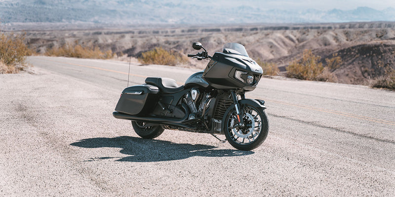 Load image into Gallery viewer, A black 2026 Indian Challenger Limited with saddlebags is parked on a paved desert road with hills and mountains in the background.
