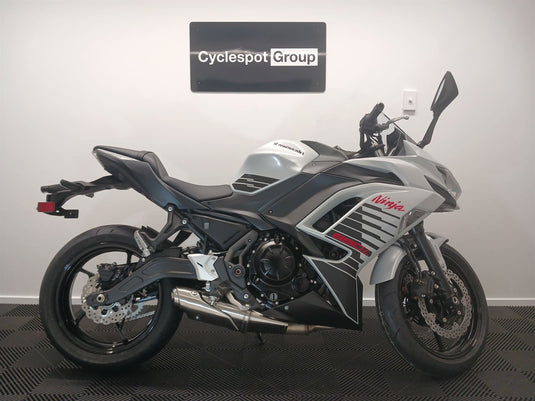 2026 Kawasaki Ninja ER 650 F in Pearl White on display with 'Cyclespot Group' sign in the background
