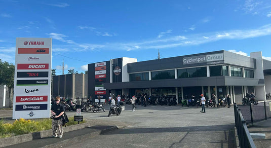 Exterior view of the Cyclespot Group Auckland flagship motorcycle dealership on a clear day, featuring prominent branding and a wide selection of motorcycles.