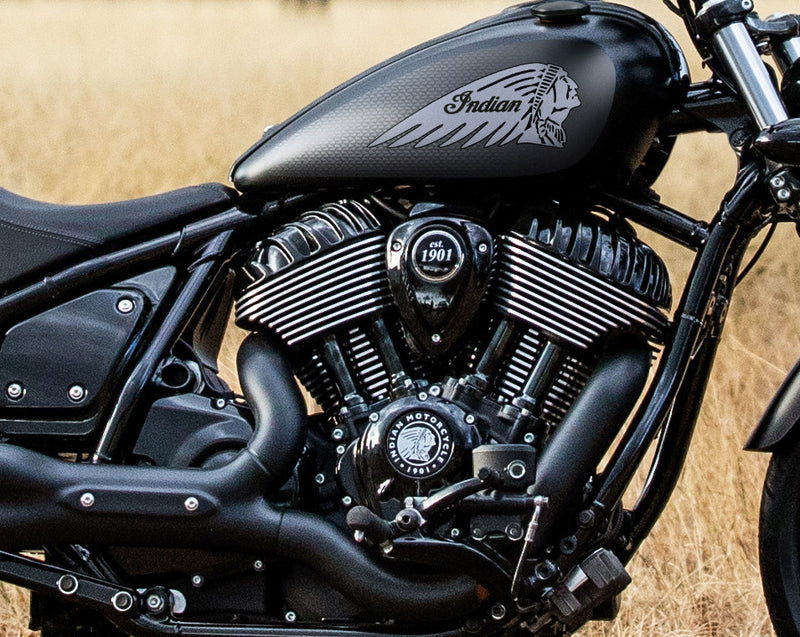 Load image into Gallery viewer, Close-up of a black 2026 Indian Chief Dark Horse motorcycle engine and fuel tank with a white Native American profile logo, photographed outdoors against a dry grassy background.
